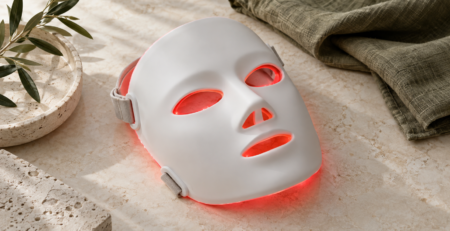 Illustratief sfeerbeeld van een wit LED-gezichtsmasker met een zachte rode gloed